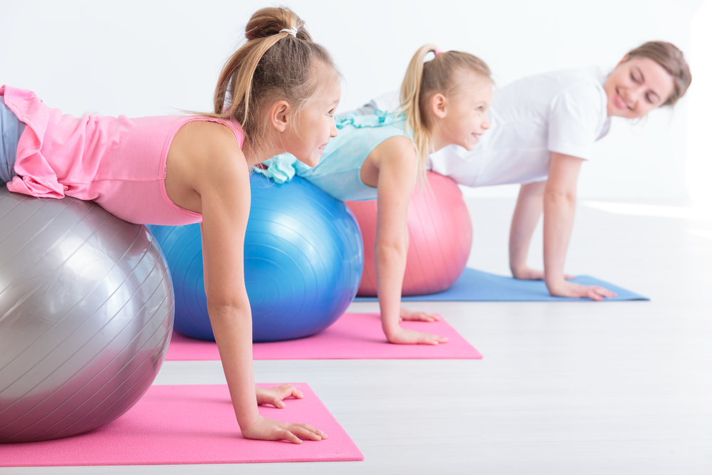 Physiotherapist and two little girls during stretching exercises